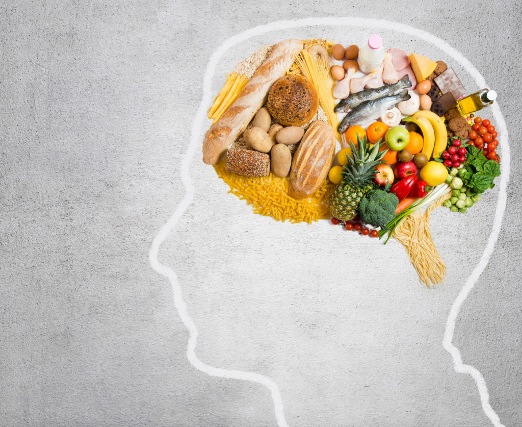 piirretty ihmisen pään muoto jonka aivot muodostuvat eri ruoka-aineista